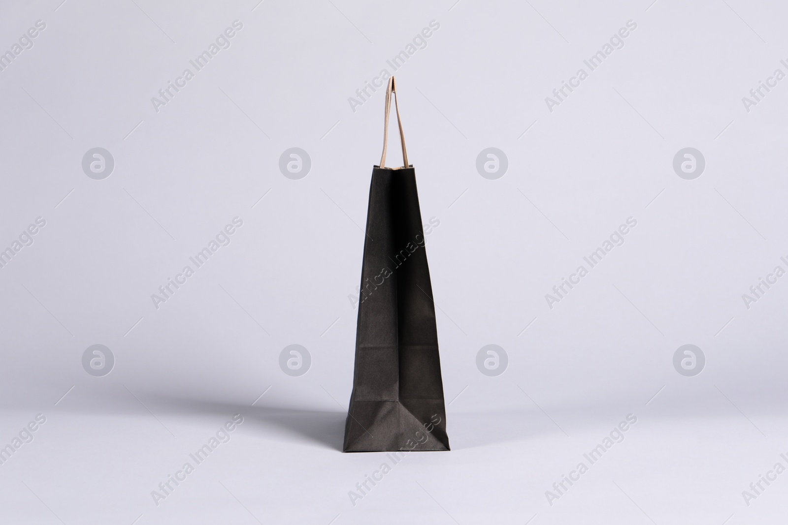 Photo of One black paper shopping bag on grey background