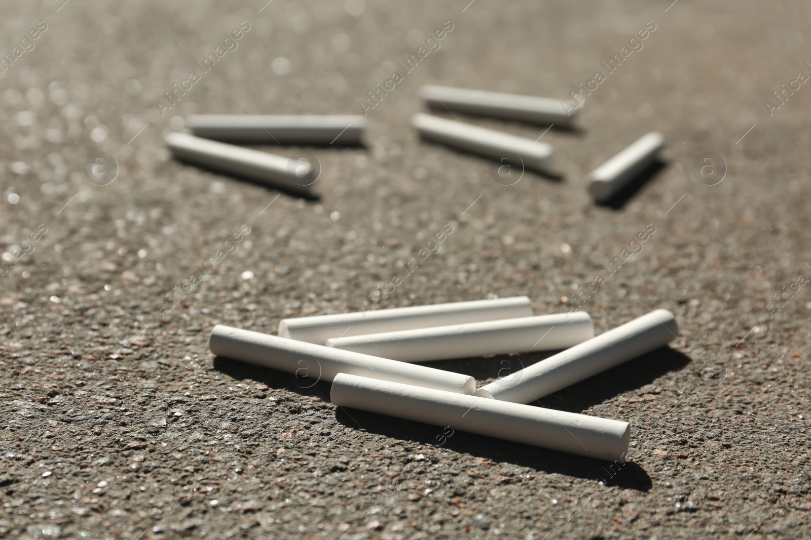 Photo of Many white chalk sticks on asphalt, closeup
