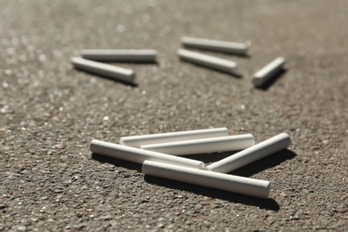 Many white chalk sticks on asphalt, closeup