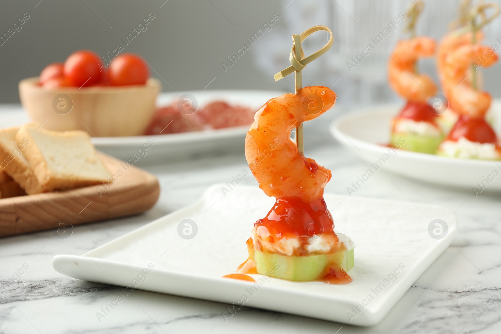 Photo of Tasty canape with shrimp, vegetables and cream cheese on white marble table, closeup