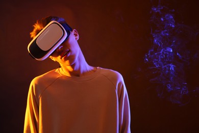 Young man with virtual reality headset on brown background