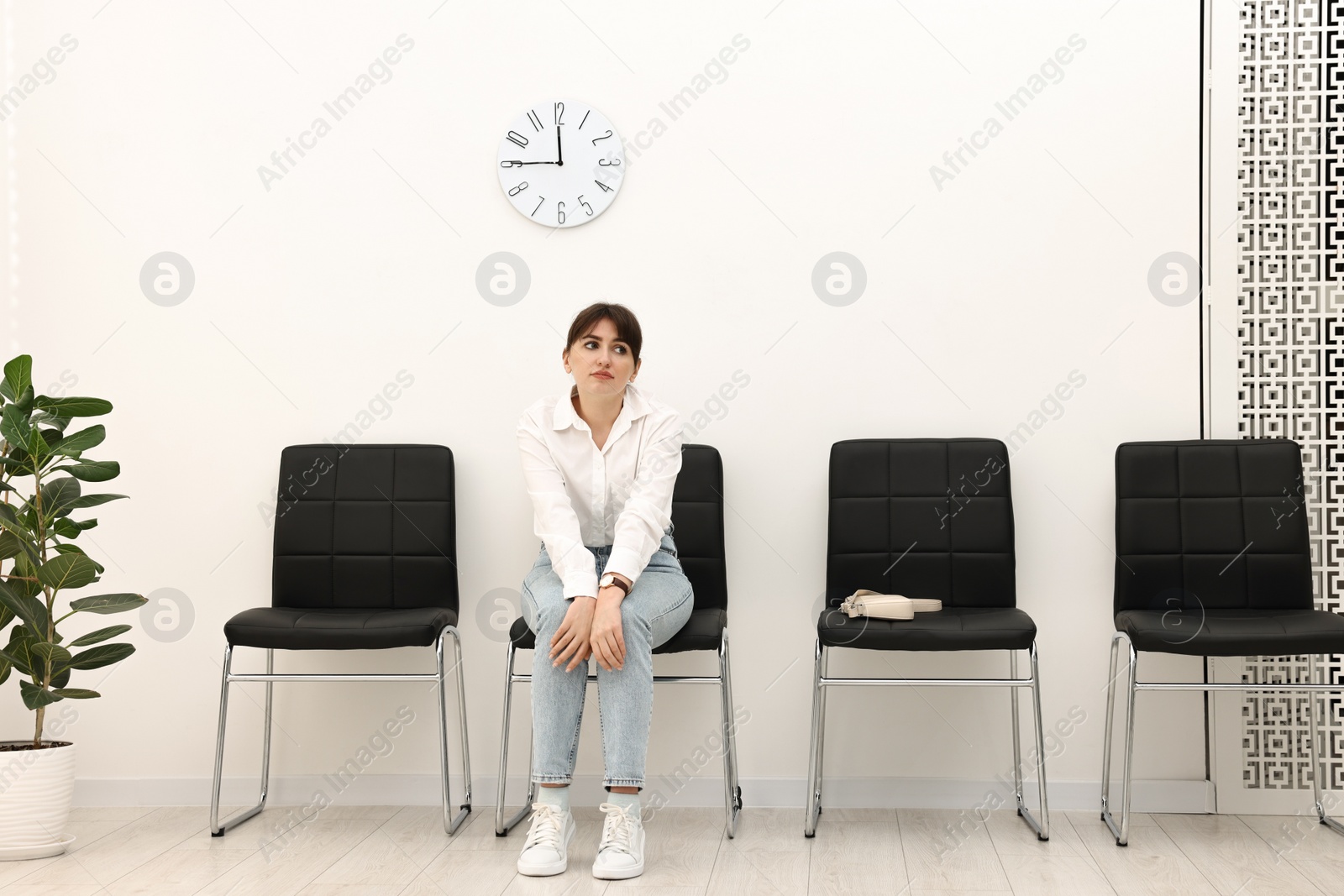 Photo of Woman sitting on chair and waiting for appointment indoors