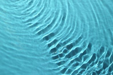 Rippled surface of clear water on light blue background, closeup