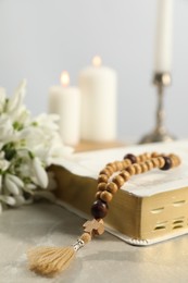 Photo of Bible, rosary beads, flowers and church candles on light table