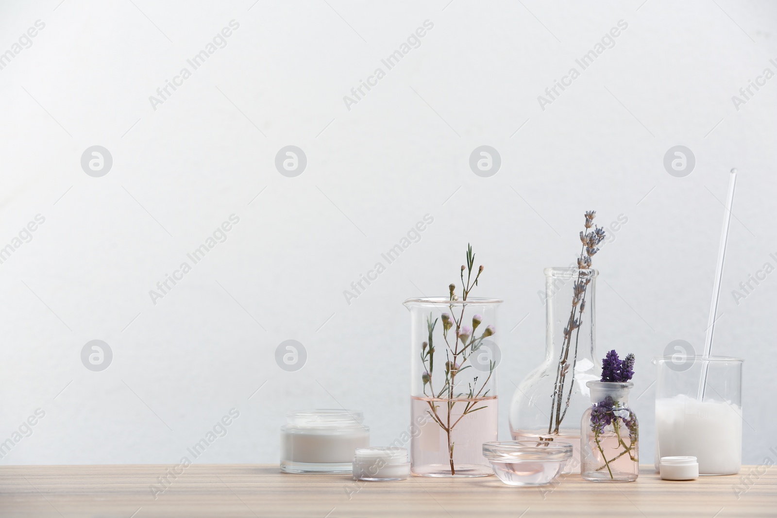 Photo of Herbal cosmetic products, laboratory glassware and ingredients on wooden table. Space for text