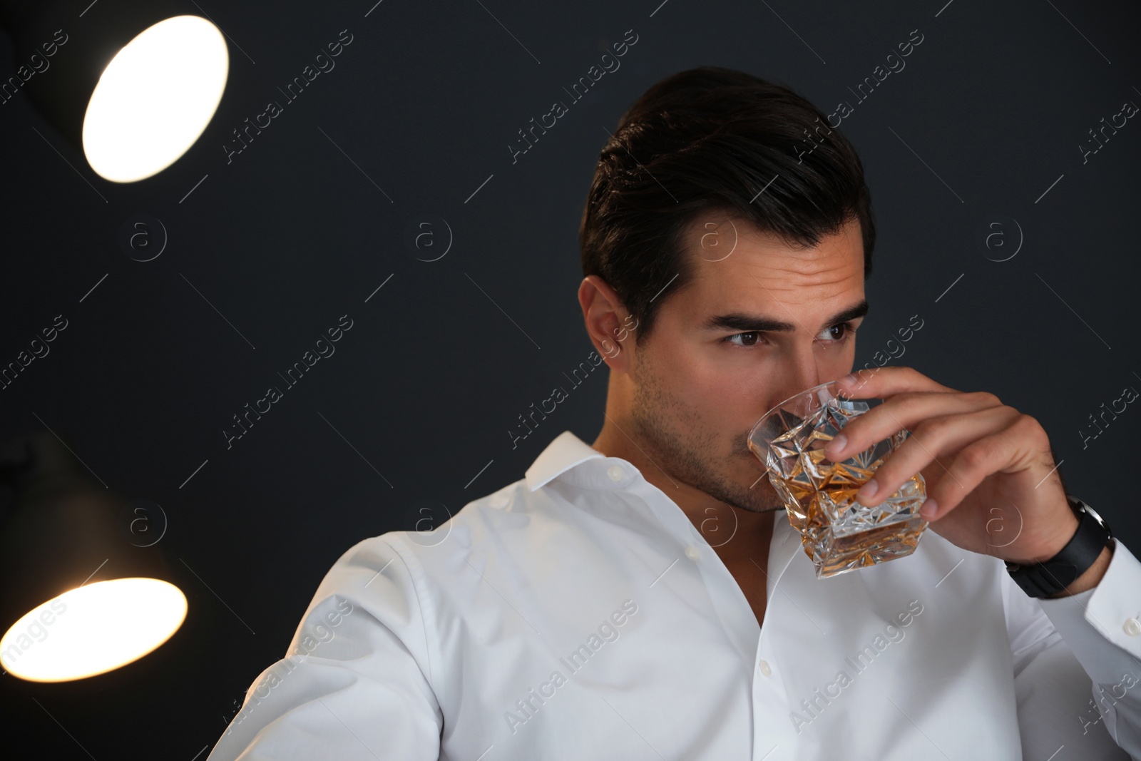 Photo of Young man with glass of whiskey on dark background