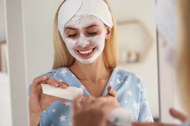 Photo of Young woman applying face mask at home. Spa treatments