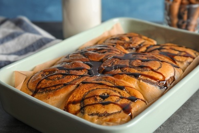 Photo of Baking dish with cinnamon rolls on table, closeup