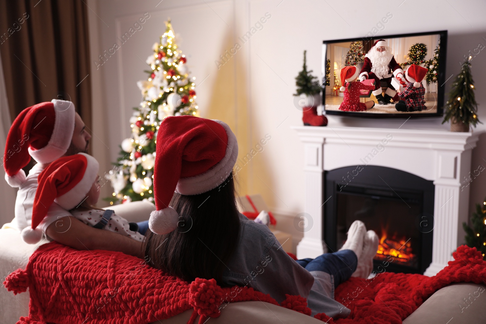 Image of Family watching festive movie on TV in room decorated for Christmas