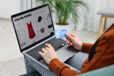 Woman with laptop and credit card shopping online at home, closeup