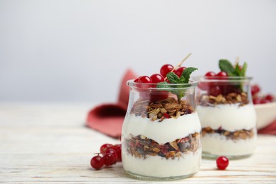 Photo of Delicious yogurt parfait with fresh red currants and mint on white wooden table, space for text