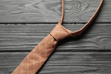 Photo of One striped necktie on black wooden table, top view