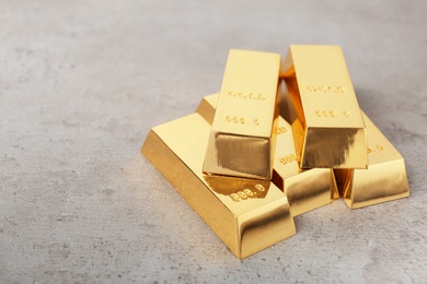Photo of Stacked shiny gold bars on table. Space for text