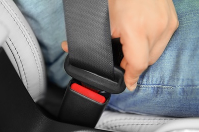 Male driver fastening safety belt in car, closeup