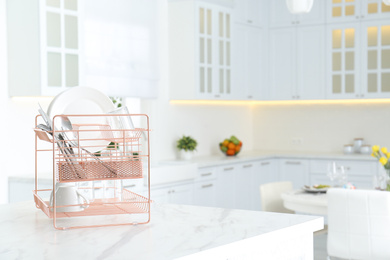 Clean dishes on drying rack in modern kitchen interior, space for text