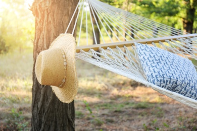 Photo of Comfortable net hammock and hat at green garden, closeup