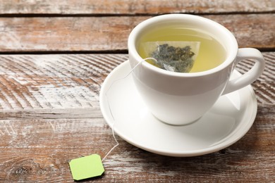 Tea bag in cup with hot drink on wooden rustic table, closeup. Space for text