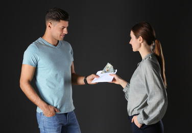 Photo of Woman giving bribe money to man on black background