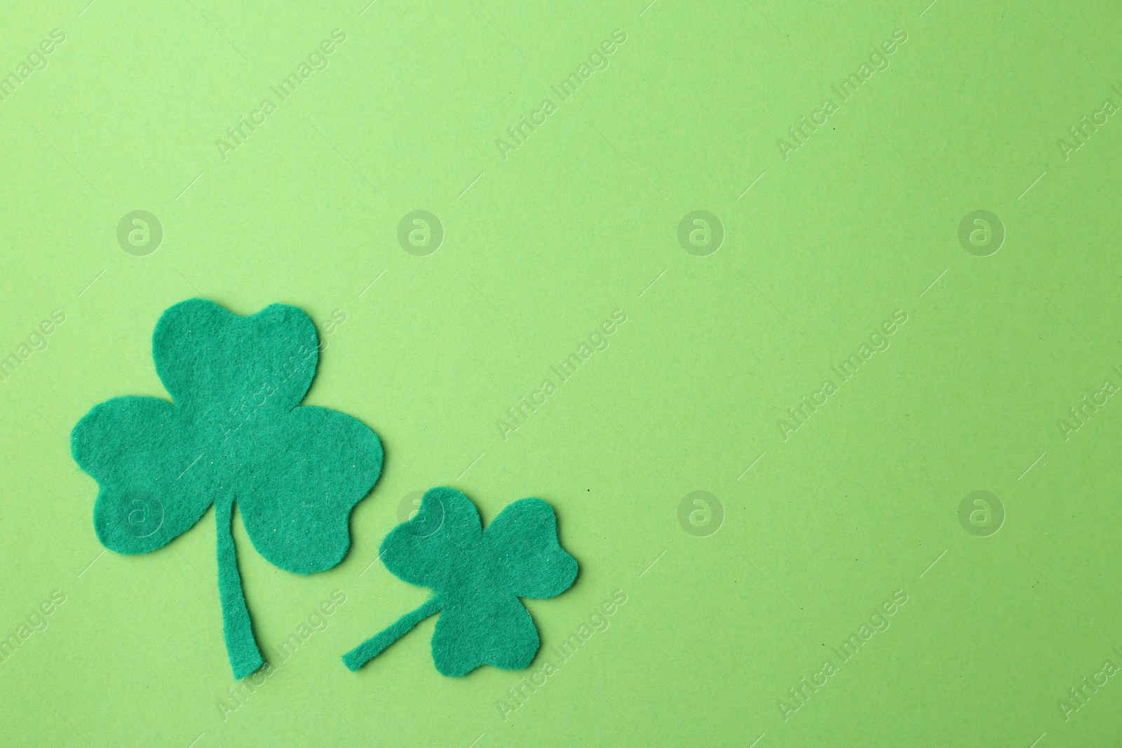 Photo of St. Patrick's day. Decorative clover leaves on green background, flat lay. Space for text