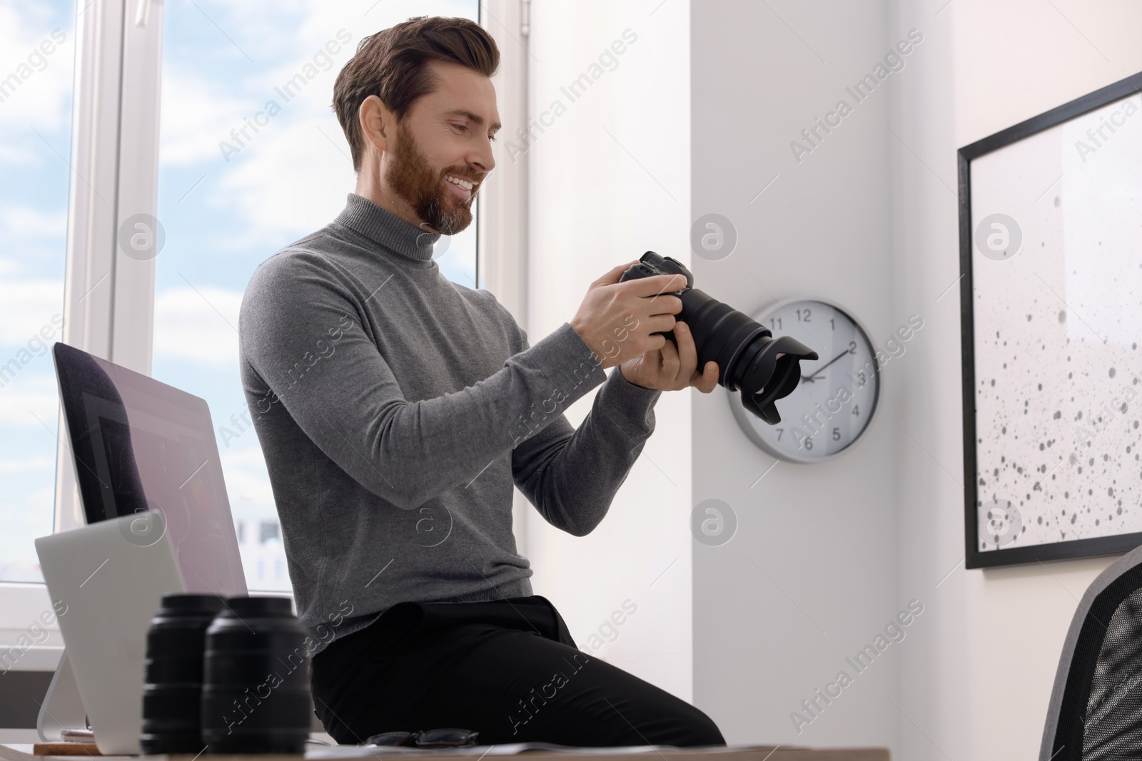Photo of Smiling professional photographer with digital camera indoors