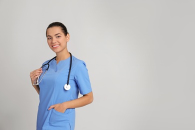 Portrait of young medical assistant with stethoscope on color background. Space for text