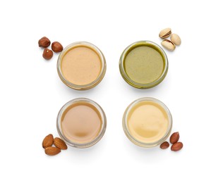 Different types of delicious nut butters and ingredients on white background, top view
