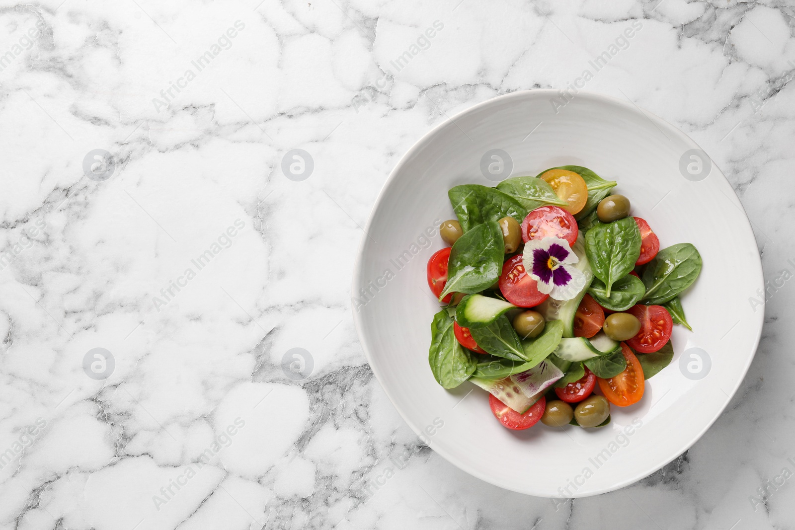 Photo of Delicious salad with vegetables and olives on white marble table, top view. Space for text