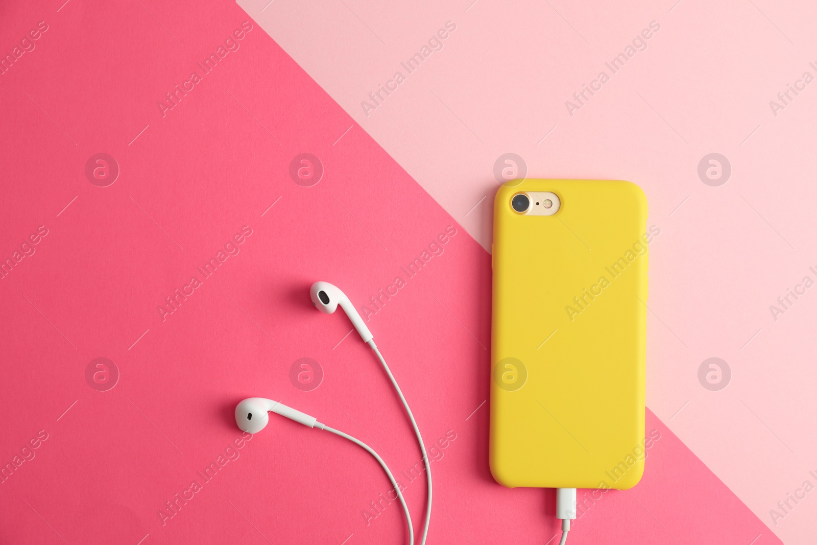 Photo of Modern phone with earphones on color background, top view. Space for text