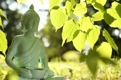Decorative Buddha statue under tree branch outdoors