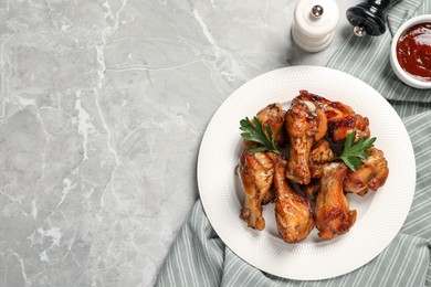 Photo of Plate with delicious fried chicken wings on light gray marble table, top view. Space for text