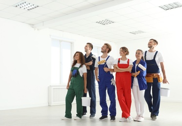 Photo of Team of professional painters with tools working indoors