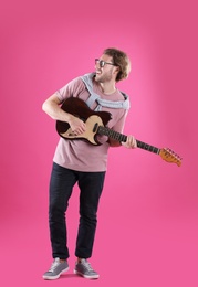 Young man playing electric guitar on color background