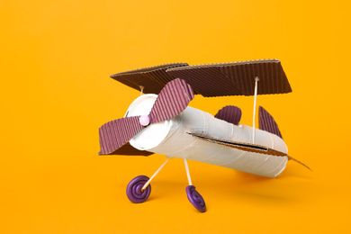 Toy plane made of toilet paper hub on yellow background