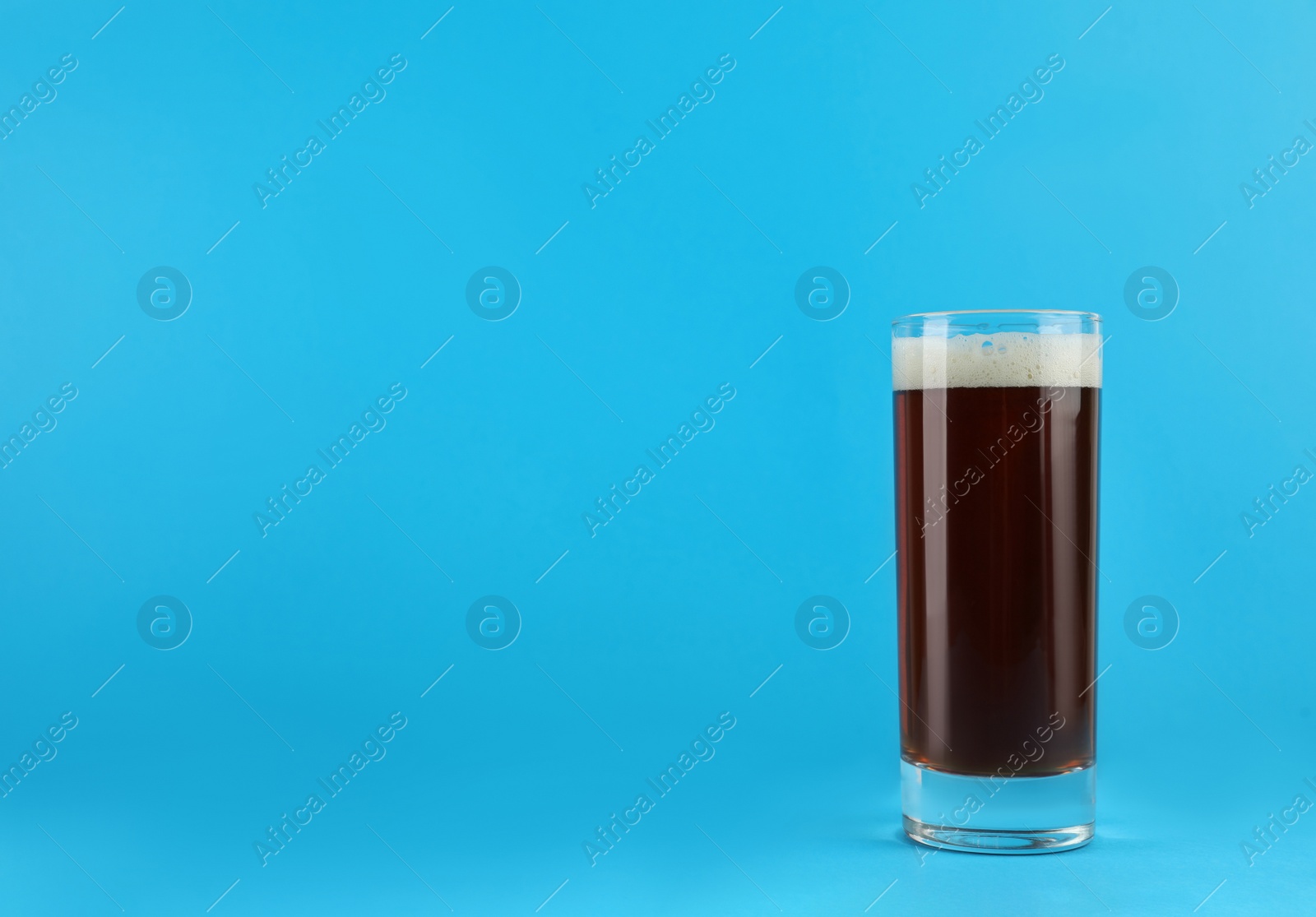 Photo of Delicious homemade kvass in glass on light blue background. Space for text