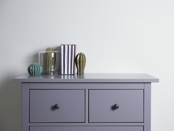 Photo of Grey chest of drawers near light wall in room