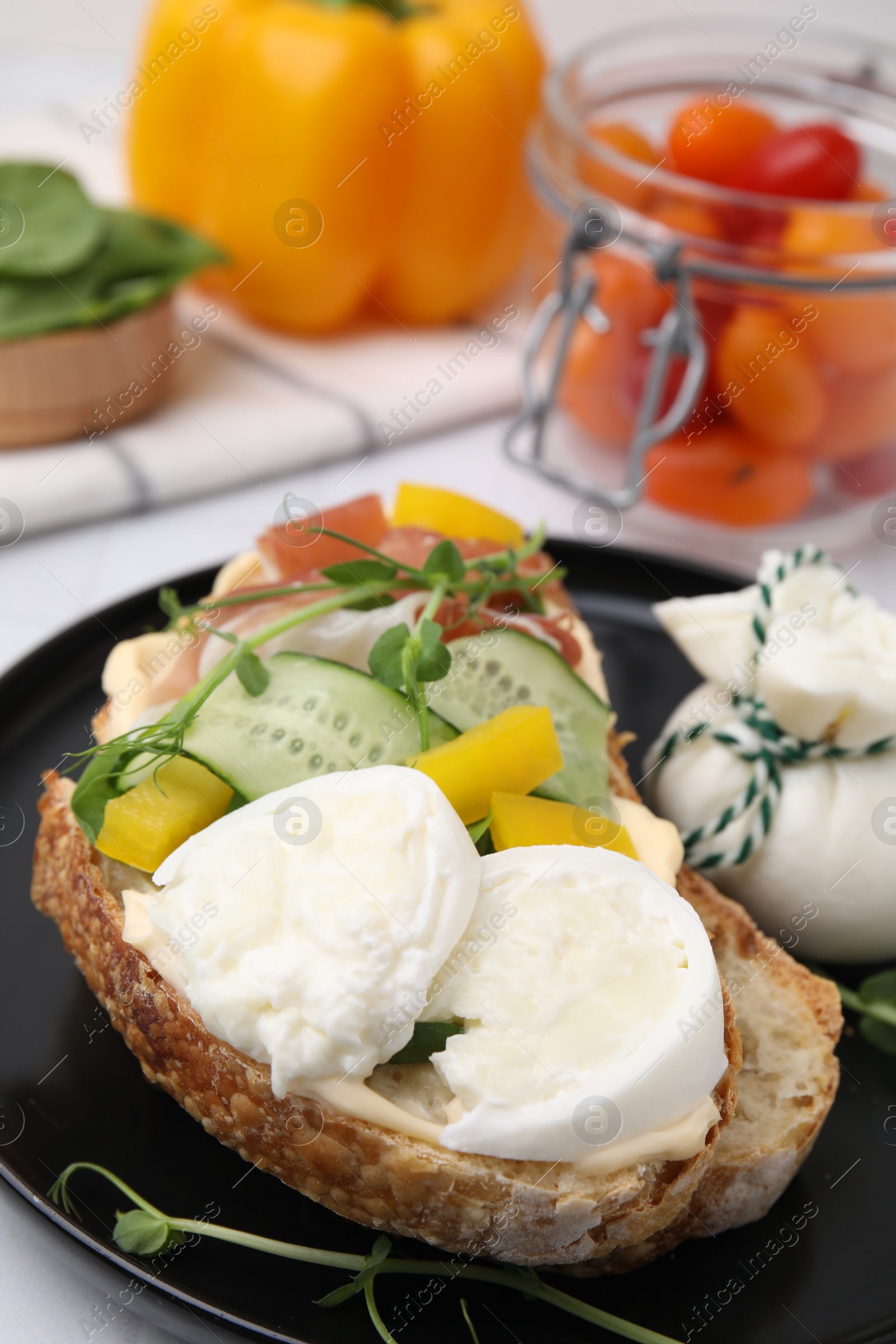 Photo of Tasty sandwich with burrata cheese, prosciutto and vegetables on table, closeup