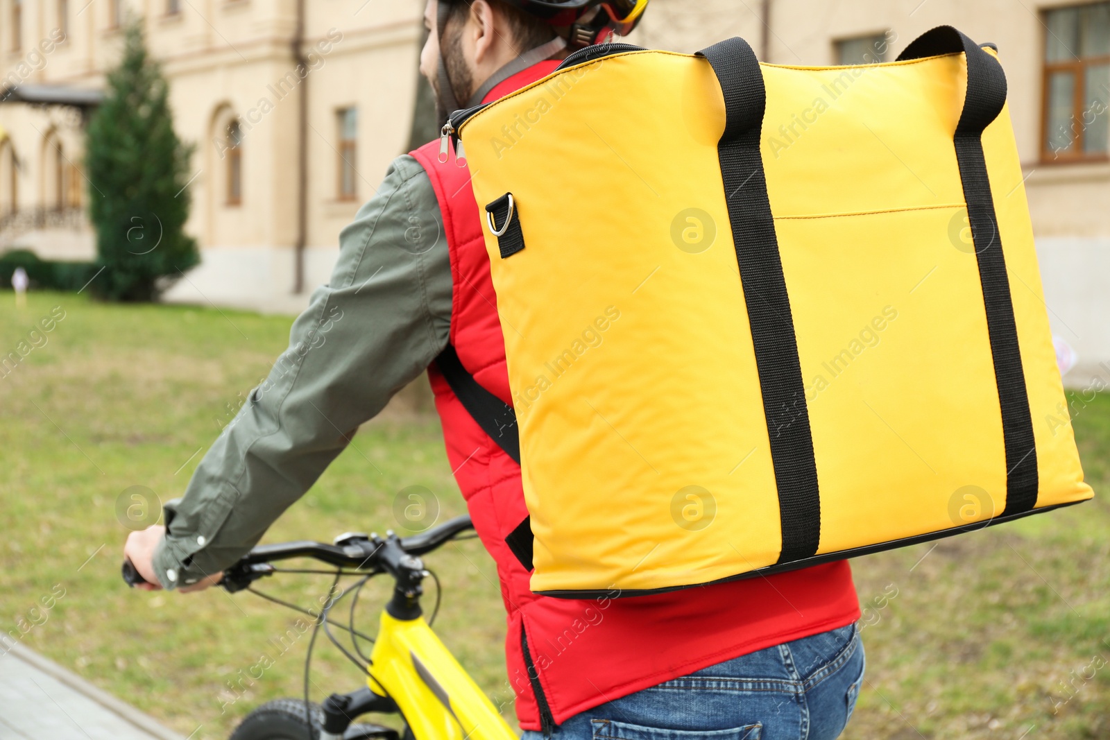 Photo of Courier with thermo bag riding bicycle outdoors, closeup. Food delivery service