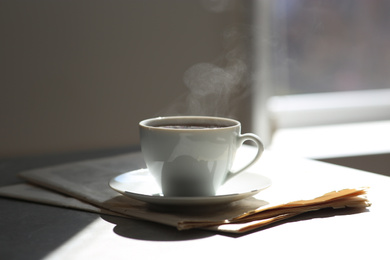 Photo of Delicious coffee and newspaper on sunlit table. Good morning