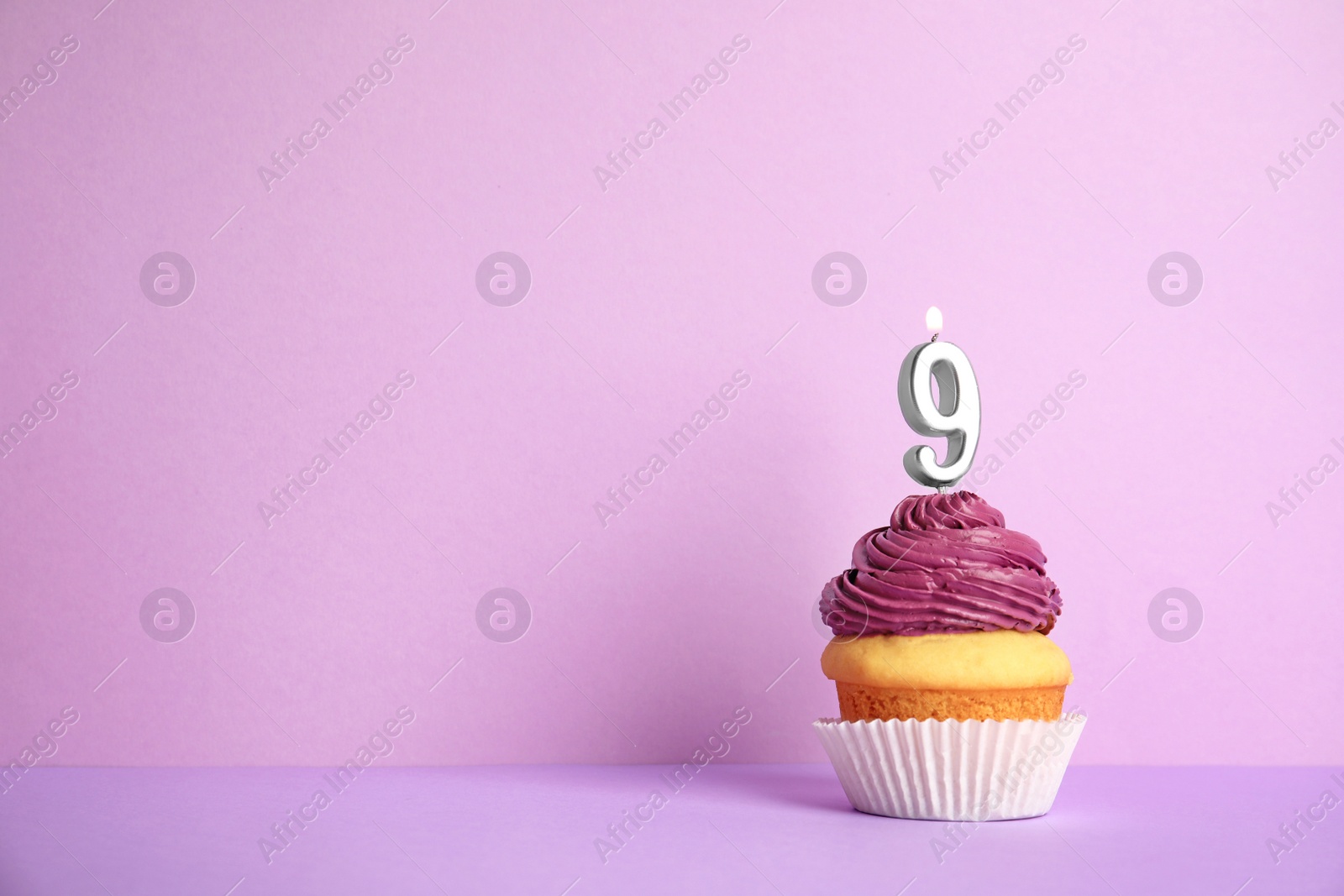 Photo of Birthday cupcake with number nine candle on violet background, space for text