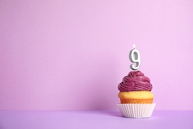 Birthday cupcake with number nine candle on violet background, space for text