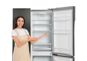 Young woman near empty refrigerator on white background