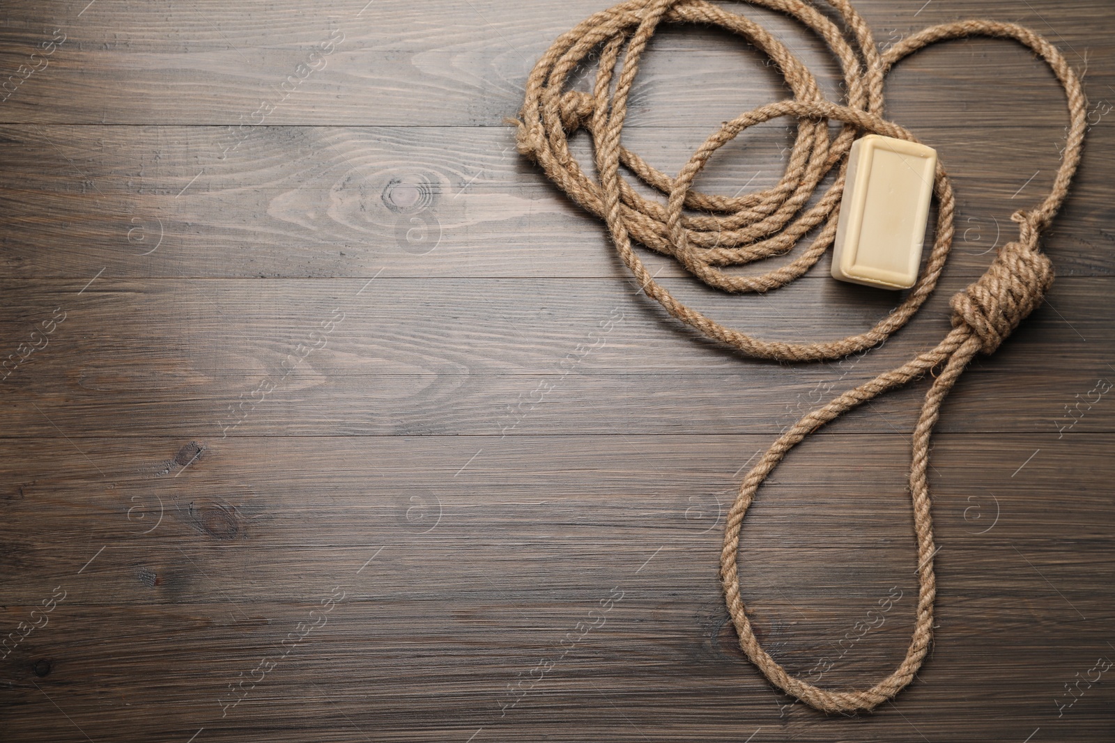 Photo of Rope noose and soap bar on wooden table, flat lay. Space for text