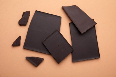 Broken chocolate bar on brown background, flat lay