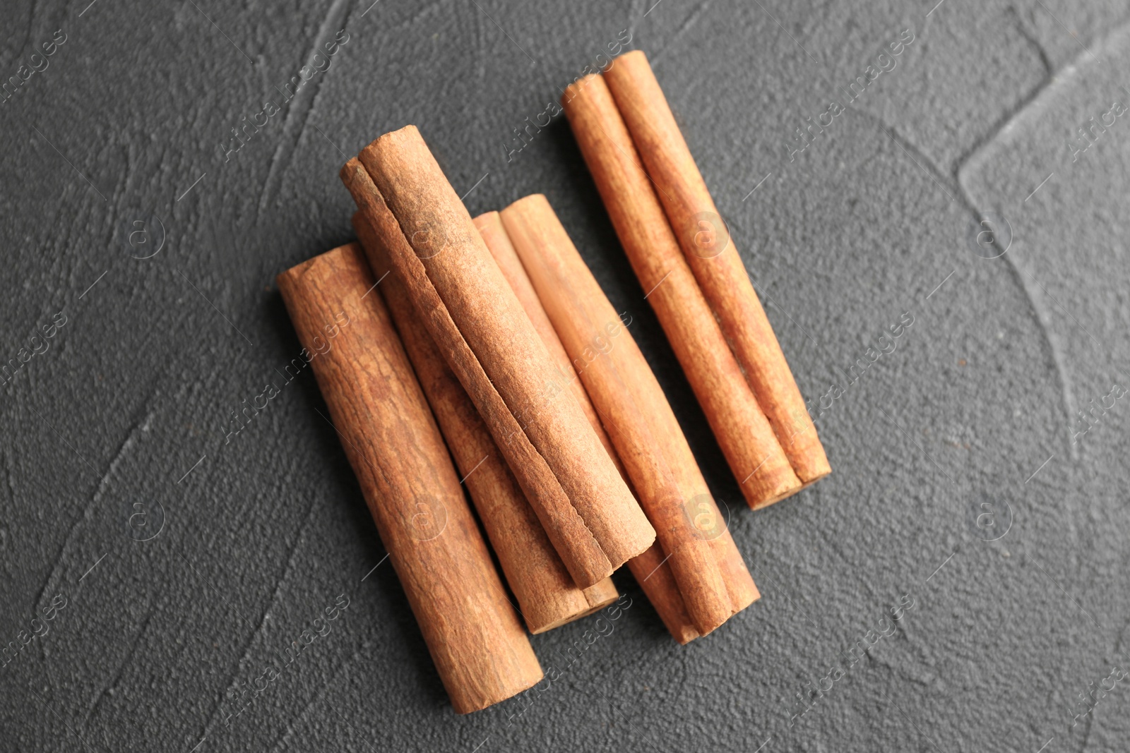 Photo of Aromatic cinnamon sticks on dark grey background