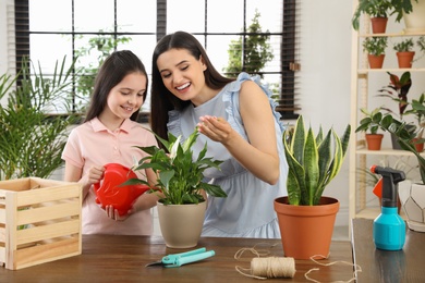 Mother and daughter taking care of plant at home