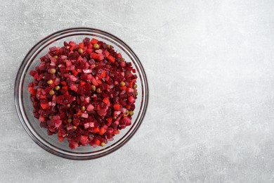 Photo of Bowl of delicious fresh vinaigrette salad on light grey table, top view. Space for text