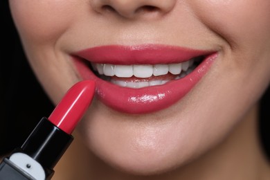 Photo of Young woman with beautiful makeup holding glossy lipstick, closeup