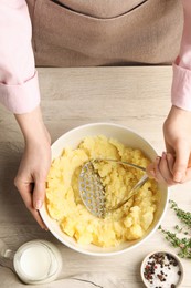 Photo of Woman making mashed potato at wooden table, top view