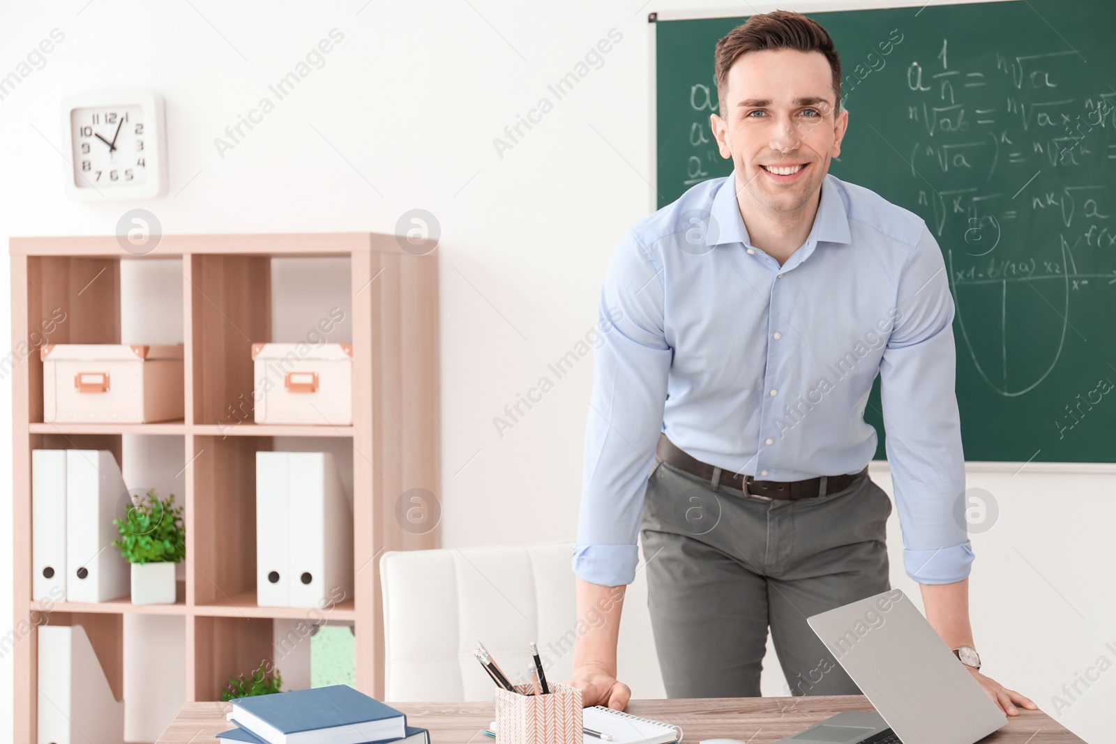 Photo of Young male teacher standing near table in classroom