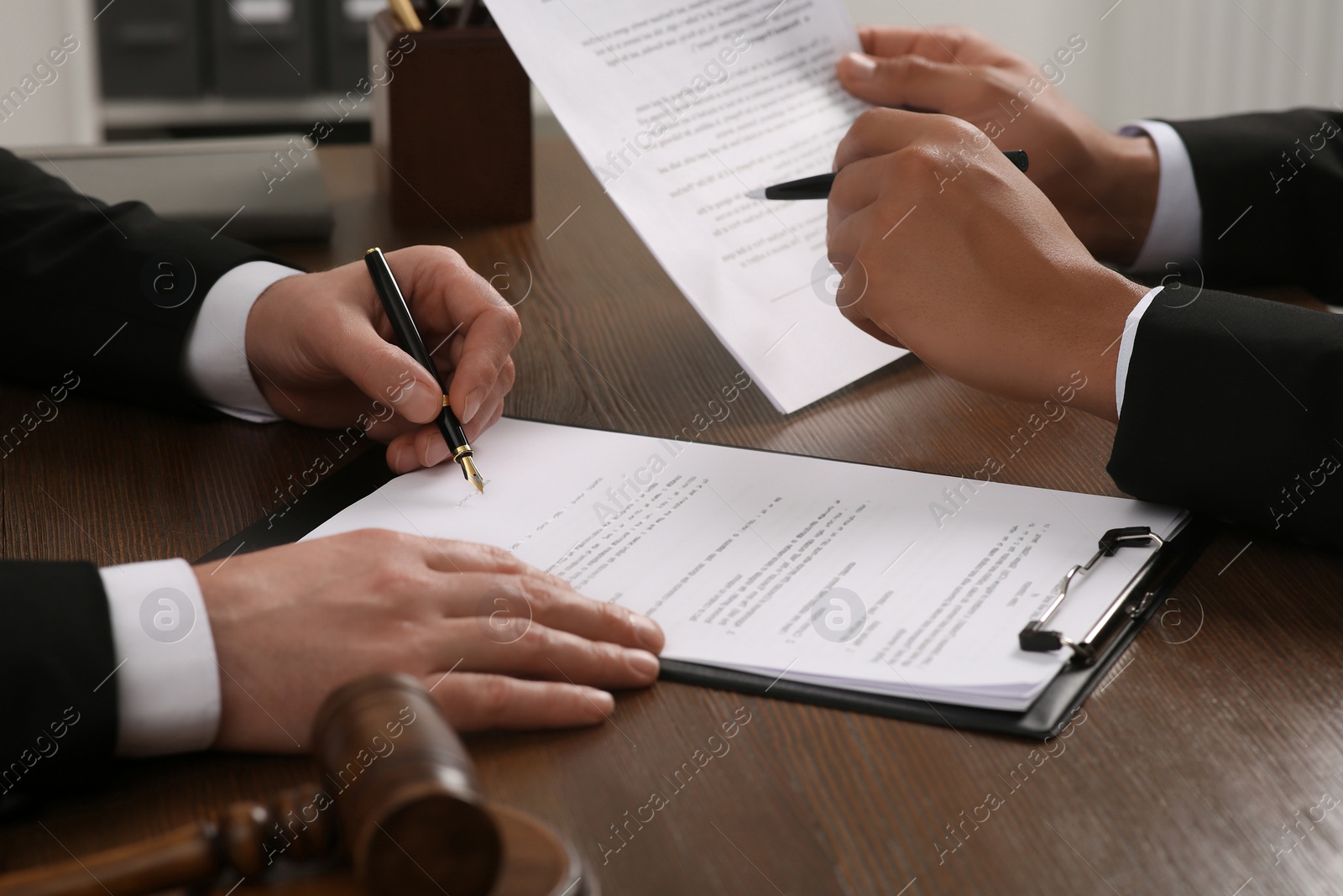 Photo of Law and justice. Lawyers working with documents at wooden table, closeup